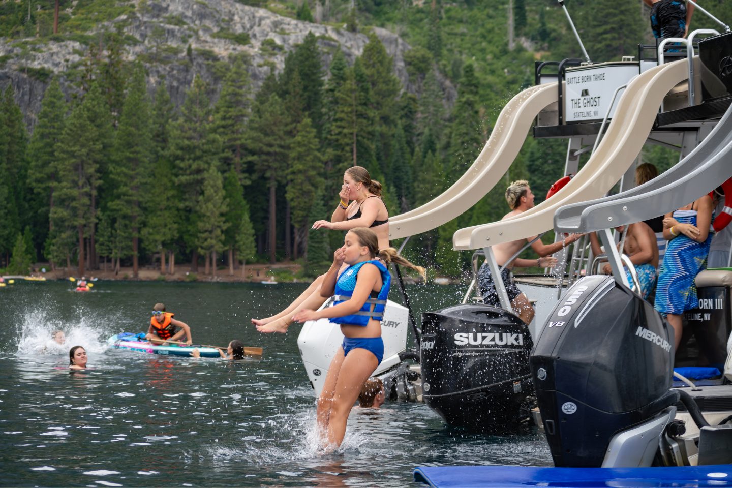 two girls use the slides on adjacent pontoon boats in lake tahoe